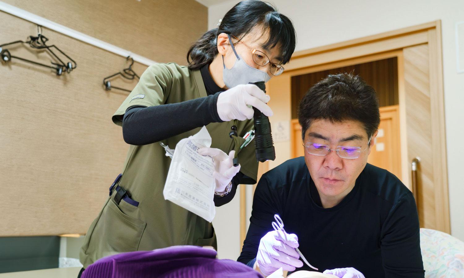 スタッフと共に訪問診療で診察をしている院長の様子